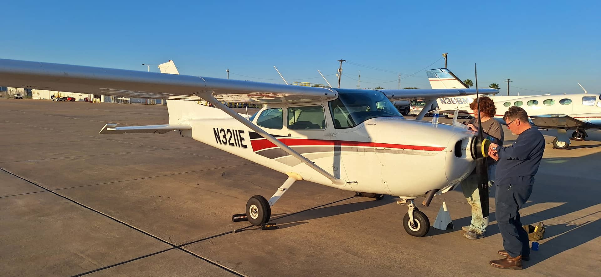 A Liberty AeroWorks mechanic working on a Cessna 172 on the ramp at golden hour