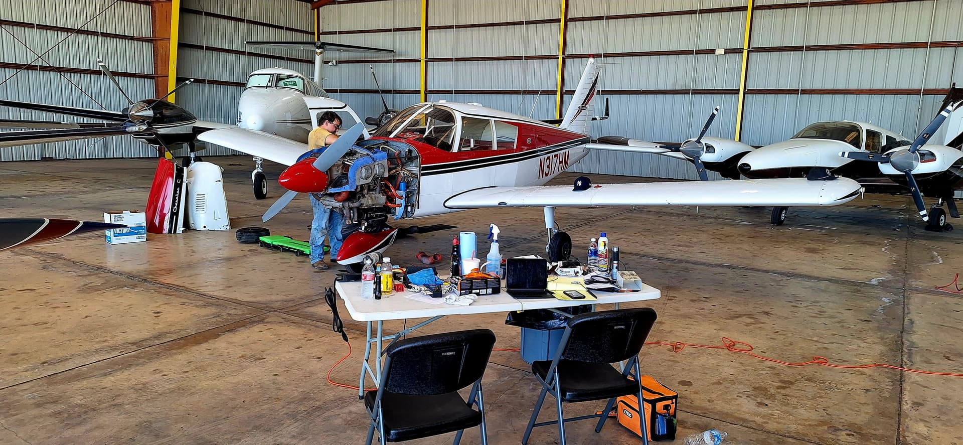 Liberty AeroWorks mechanic working an engine on a Piper inside a customer's hangar