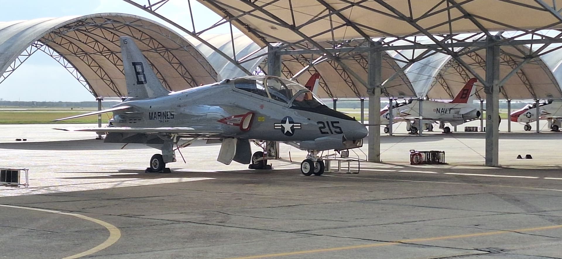 Military trainer aircraft staged on the flightline under sun shelters